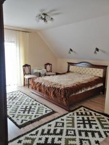 a bedroom with a large bed and a rug at Pensiunea Baias in Bîrsana