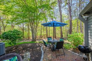 a patio with a table and chairs and an umbrella at Sea Spark - Cape Escape with Pool Access in Mashpee