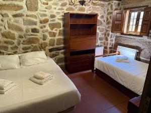 two beds in a room with a stone wall at Casa do Campo in Montalegre