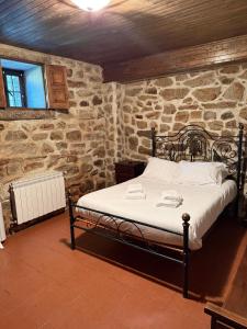 a bedroom with a bed in a stone wall at Casa do Campo in Montalegre