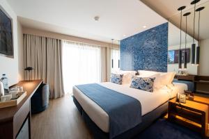 a hotel room with a bed with a blue wall at Jupiter Porto Hotel - Rooftop & Spa in Porto