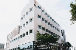 a white building with a tree in front of it at Jupiter Porto Hotel - Rooftop & Spa in Porto