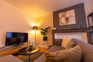 a living room with a couch and a flat screen tv at L'échappée de l'Arbalète in Autun