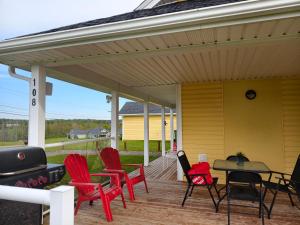 a patio with red chairs and a table on a yellow house at Near Cavendish Beach-1 in Stanley Bridge