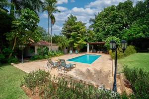 a swimming pool in a yard with chairs and a house at Las Margaritas, Casa de Campo in La Romana