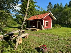 a red cabin with a picnic table and a bench at Salatse metsa mesionn in Salatse