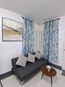 a couch in a room with blue curtains and a table at Sorelle Bella Vita in Manolo Fortich