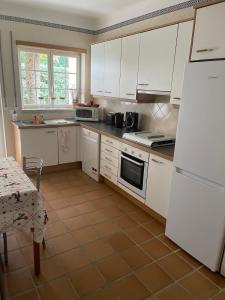 a kitchen with white cabinets and a white refrigerator at Casa Lesarlo - T3 luxury, garden, pool - Praia D'El Rey in Casal da Lagoa Seca