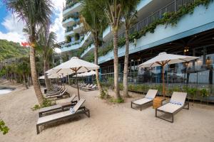 a beach with chairs and umbrellas and a building at Flamingo Cát Bà in Cat Ba