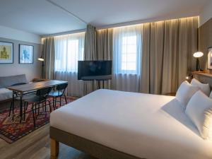a hotel room with a large bed and a desk at Novotel Suites Nice Airport in Nice