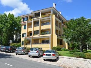 een groot geel gebouw met auto's geparkeerd voor het bij Alegre Apartamento in Cascais