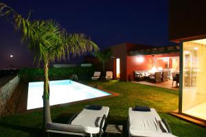 a swimming pool with two lounge chairs and a palm tree at Villa Salobre Master and Sun in Maspalomas
