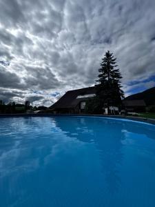 a large blue swimming pool under a cloudy sky at Gut im Schlag in St. Wolfgang