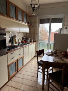 a kitchen with white cabinets and a table and a dining room at Spacious Apartment 20min from Piazza Maggiore in Bologna