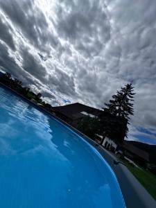 a blue swimming pool with a cloudy sky in the background at Gut im Schlag in St. Wolfgang