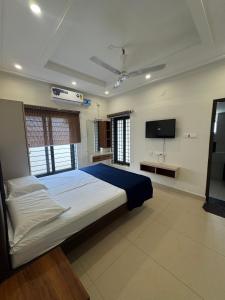 a bedroom with a large bed and a flat screen tv at JSP OLIVE NEST villa in Yelagiri