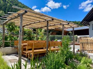 a wooden pergola with a wooden bench in a garden at Unterlechnerhof in Vollan