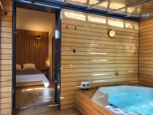 a bathroom with a tub and a bed in a room at Le mazet des amants, cabane en bois avec jacuzzi privatif in Avignon