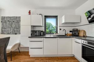 a kitchen with white cabinets and a window at Design-Apartment mit Garten in Langenbach
