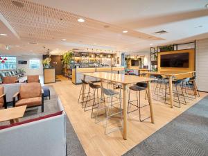 a restaurant with a large wooden table and chairs at ibis Hamilton Tainui in Hamilton