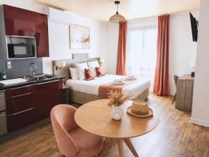 a hotel room with a bed and a table and a kitchen at Hôtel La Maison des Croisades - Au pied des Remparts in Aigues-Mortes