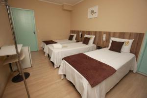 a hotel room with two beds and a sink at Gru Inn Hotel in Guarulhos