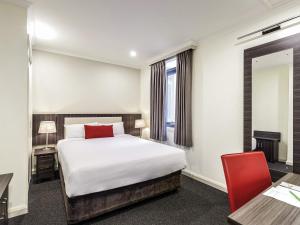 a hotel room with a bed and a red chair at ibis Styles Kingsgate Melbourne in Melbourne +46 photos