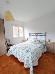 ein Schlafzimmer mit einem Bett mit einer geblümten Tagesdecke in der Unterkunft A Esteva in Orol