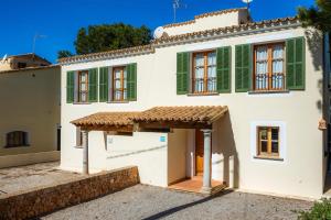 a white house with green shutters at Cala Pi One in Cala Pi