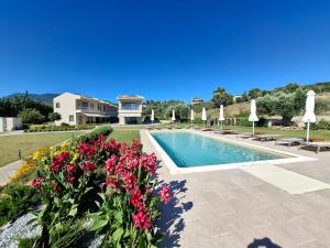 a villa with a swimming pool with flowers and umbrellas at SeaSide Village in Politika