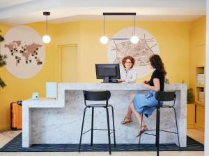 two women sitting at a counter with a computer at Aparthotel Adagio Aix-en-Provence Centre in Aix-en-Provence