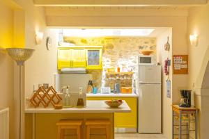 a kitchen with yellow cabinets and a white refrigerator at Villa Verde Petra in Rethymno