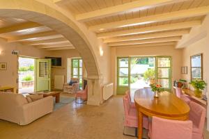 a living room with a wooden table and pink chairs at Villa Verde Petra in Rethymno +28 photos