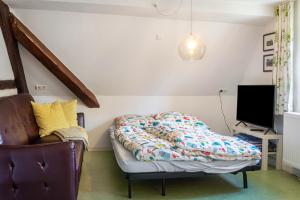 a bed in a room with a chair and a tv at Alte Schmiede Ellrichshausen 2 in Satteldorf