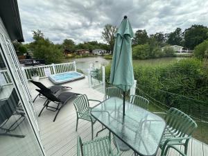 a patio with a table and a green umbrella at Luxury Lakeside Lodge L2 with Hot tub situated at Tattershall Lakes Country Park in Tattershall