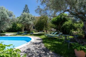 a yard with a pool and chairs and trees at VK Villas in Apolpaina