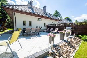 a patio with chairs and a grill and a house at Willa u Basi in Miłków