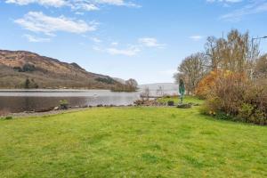 a grassy field next to a body of water at 2 Bed in St. Fillans oc-a40242 in Saint Fillans