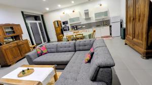 a living room with a gray couch and a kitchen at Patissou in Solignac