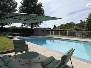 a pool with two chairs and a table and an umbrella at Patissou in Solignac