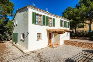 an exterior view of a white house with green shutters at Cala Pi Two in Cala Pi
