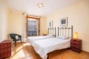 a bedroom with two beds and a chair and a window at Cala Pi Two in Cala Pi