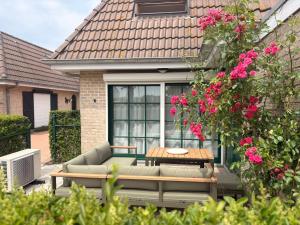 a patio with a couch and a table and pink flowers at Maison Lavandelle in Middelkerke