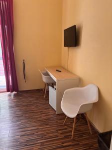 a room with a desk with two chairs and a television at Y Panzió in Balatonlelle