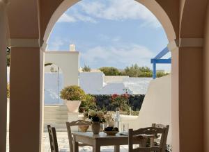 an archway leading into a patio with a table and chairs at White Pearl Laokasti Suites in Oia