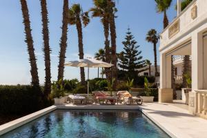 a swimming pool with chairs and an umbrella and palm trees at Maison Gioia di Casa Camilla Journey in Capilungo
