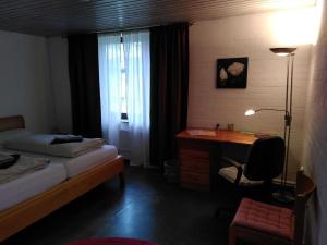 a bedroom with a bed and a desk and a window at Gästewohnung am Sternberg in Gomadingen