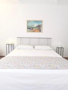 Ein weißes Bett in einem Schlafzimmer mit einem Bild an der Wand in der Unterkunft Appartamento in Monferrato di Dominga in Portacomaro