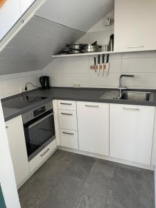 a white kitchen with white cabinets and a sink at Moderne Ferienwohnung mit Balkon und Klima in Neufraunhofen
