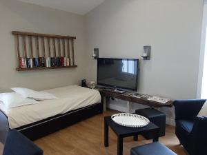 a room with a bed and a tv and a chair at La Mariennaye in Beaurepaire